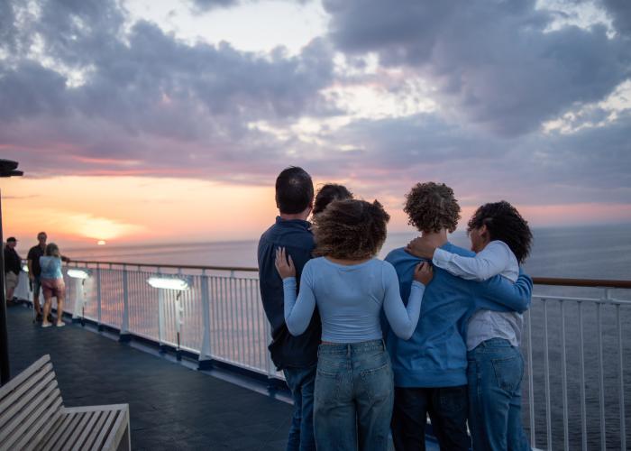 A family embraces each other as they watch the distant sunset