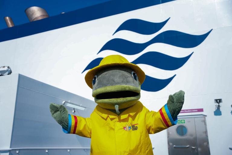 A mascot of a fish in yellow rain jacket and matching hat poses in front of the Marine Atlantic logo.